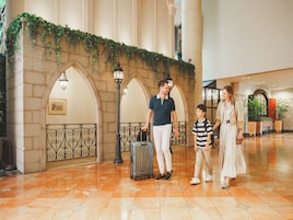 A lobby with a tiled floor, a wall with greenery, and a black metal railing.