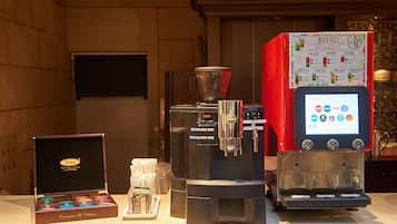 Una cafetera con pantalla de menú, un molinillo de café y una caja de cápsulas de café.