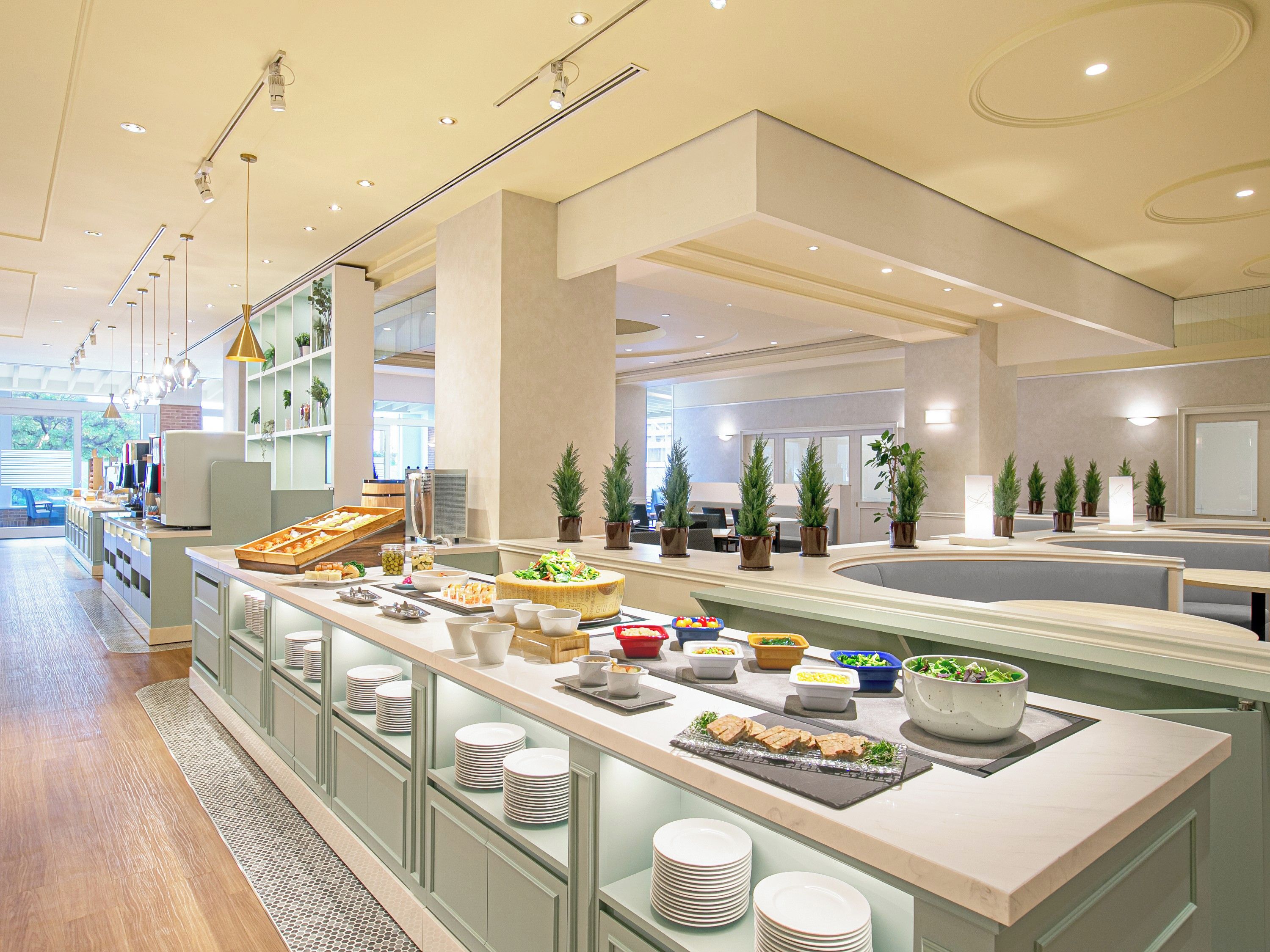 Un moderno vestíbulo de hotel con zona de buffet, asientos y vistas al exterior.