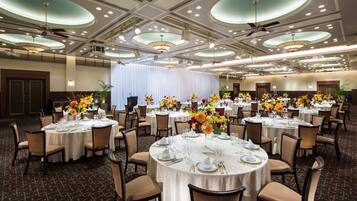 A banquet hall with round tables set for dining, featuring white tablecloths and floral centerpieces.