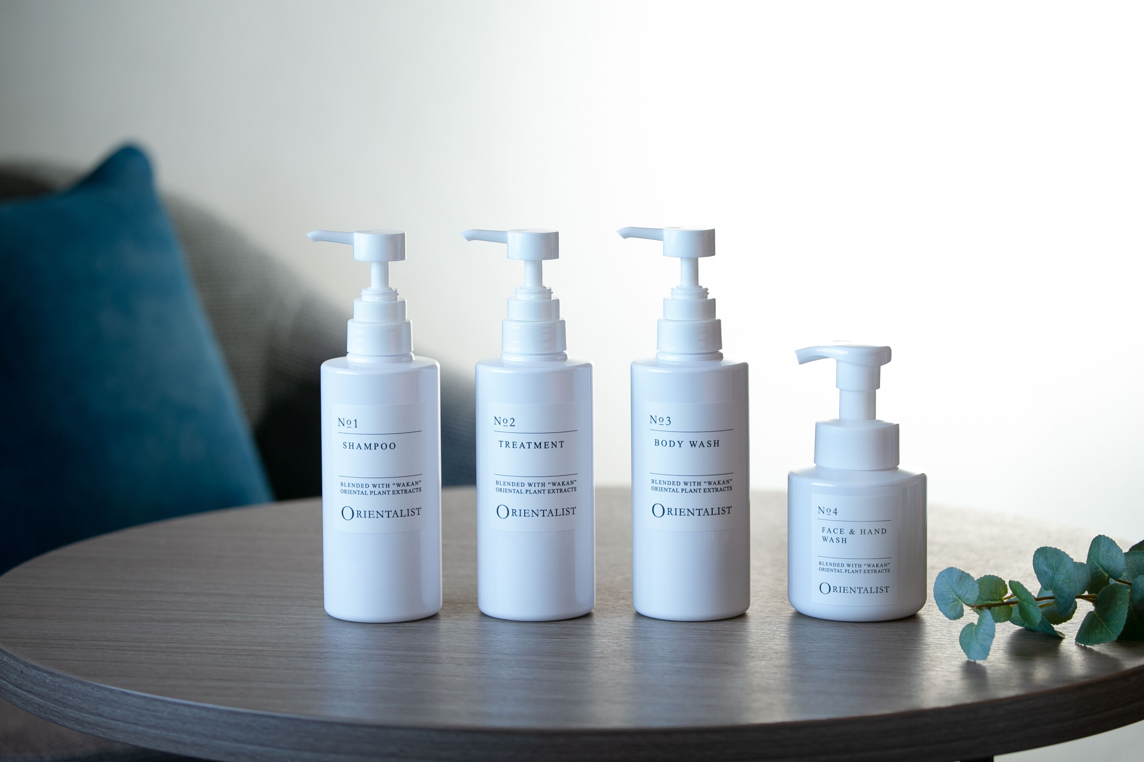 Four bottles of Orientalist skincare products on a round table.