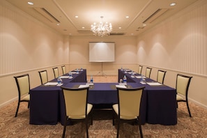 A conference room with a long table, chairs, a projector screen, and a chandelier. - Oriental Hotel Tokyo Bay (Urayasu)