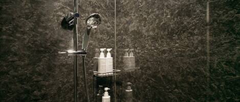 Un baño moderno con cabina de ducha de vidrio, paredes de mármol y un estante con artículos de aseo.