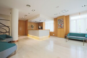 A spacious lobby with a reception desk, seating area, and a staircase.