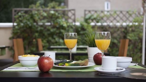 Un desayuno con una mesa, platos, tazones y vasos de jugo de naranja.