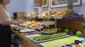 Un bufé con diversos alimentos, incluyendo frutas, pasteles y pan.