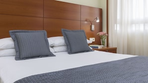 Una cama bien hecha con un edredón acolchado, dos almohadas y un cabecero de madera.