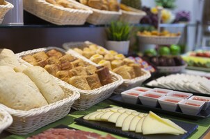 A buffet with various food items including bread, cheese, and fruit.