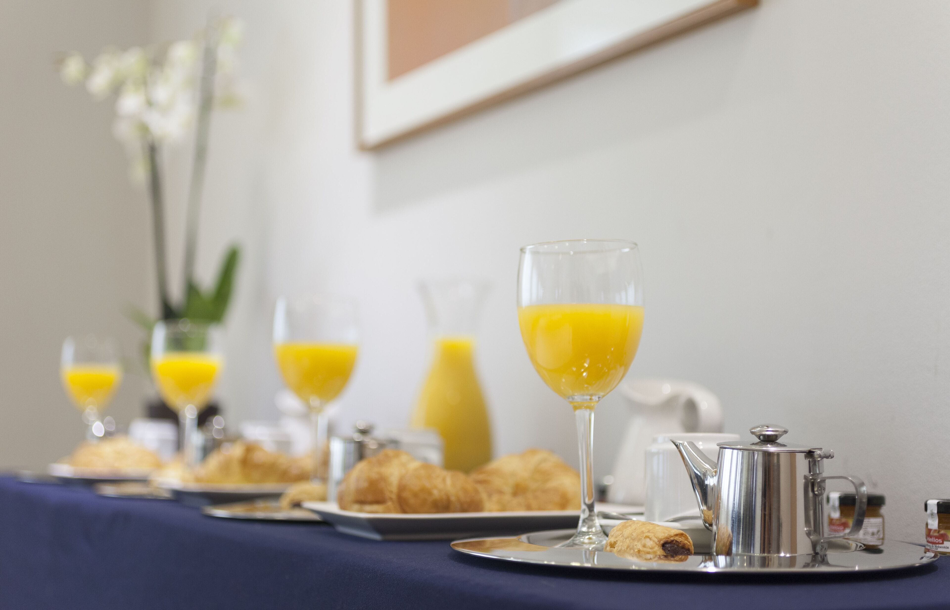 A breakfast setup with croissants, orange juice, and a coffee pot on a tray.