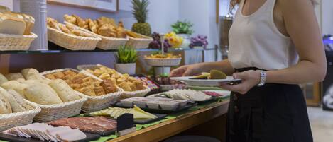 Un bufé con diversos alimentos, incluyendo pan, carnes y frutas.
