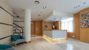Un vestíbulo moderno con un mostrador de recepción, zona de estar y una escalera.