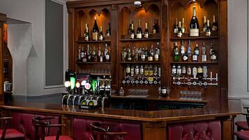 A bar area with multiple liquor bottles, a selection of beers, and a variety of glasses.