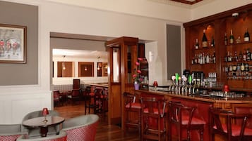 A bar area with wooden furniture, a bar counter, and a variety of bottles and glasses.