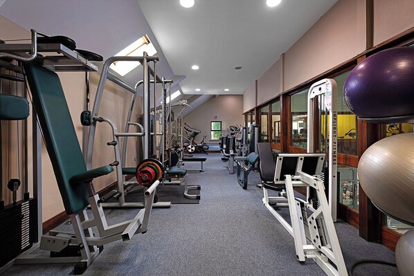 A gym with various exercise equipment, including weight machines and cardio machines, arranged in a spacious layout.