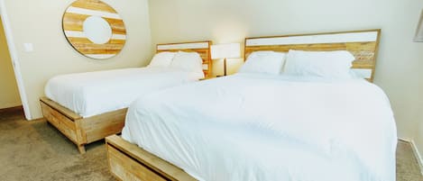 Een hotelkamer met twee bedden, een houten hoofdeinde, een ronde wanddecoratie en een vloerbedekking.