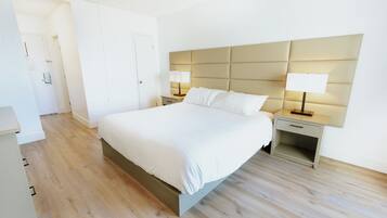 Une chambre à coucher moderne avec un grand lit, deux tables de chevet avec des lampes et une armoire.