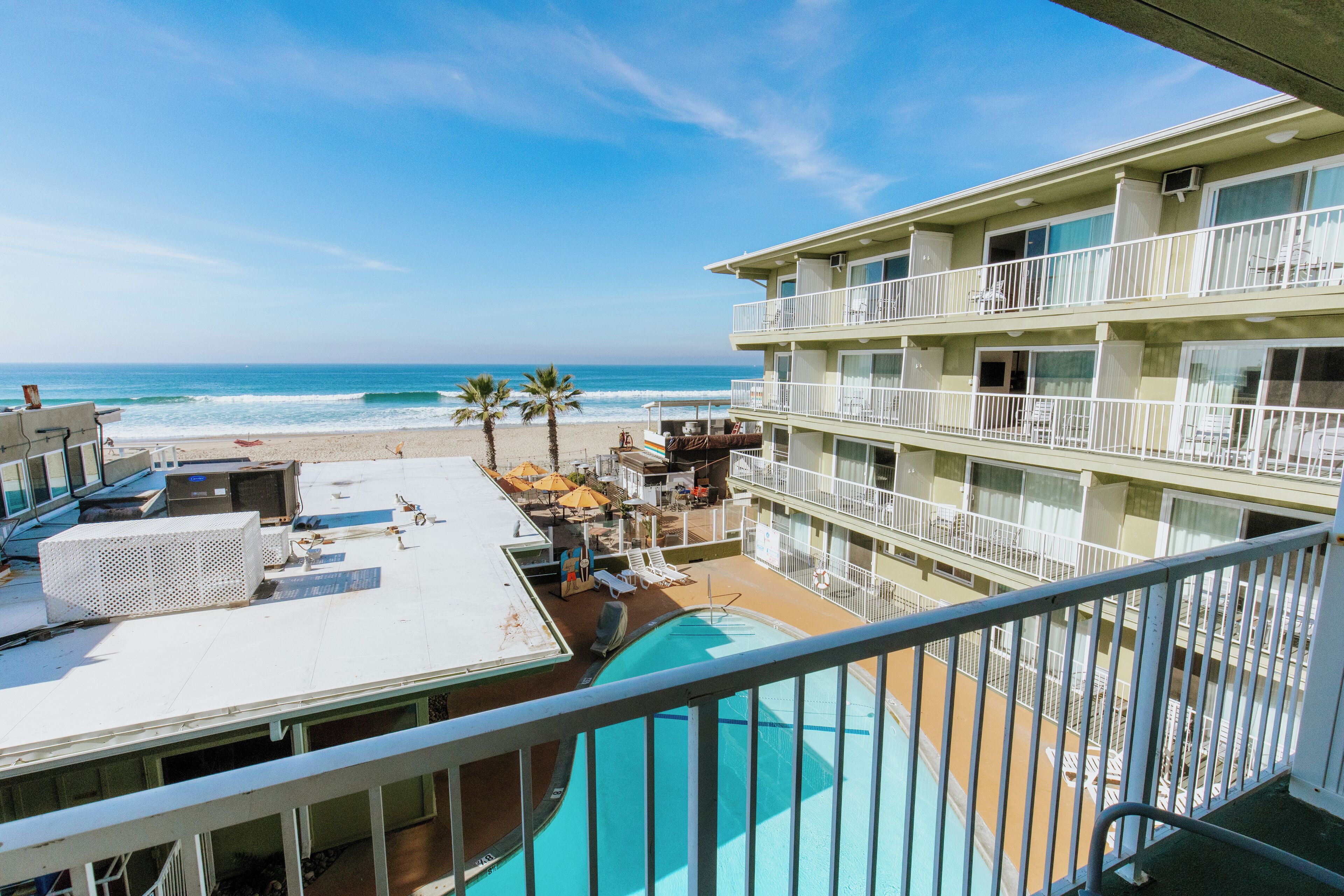 A hotel with a pool, beach view, and multiple balconies.