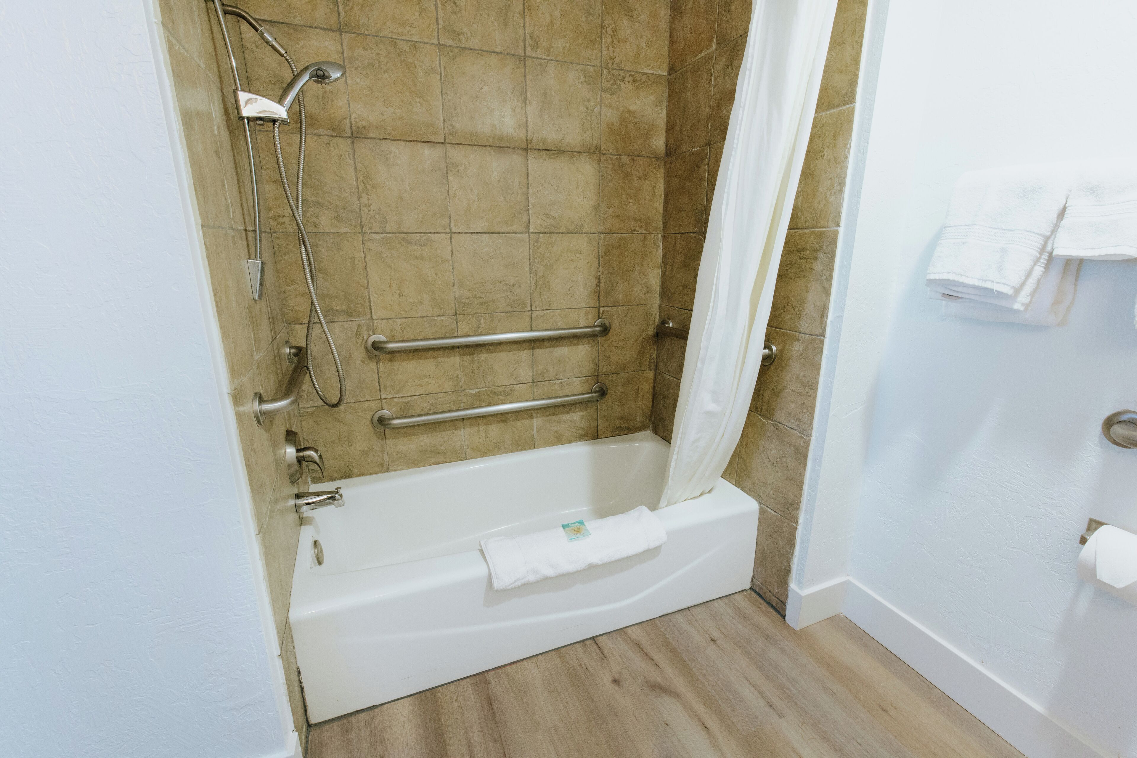 Une salle de bain équipée d’une baignoire, d’une douche et de barres d’appui.