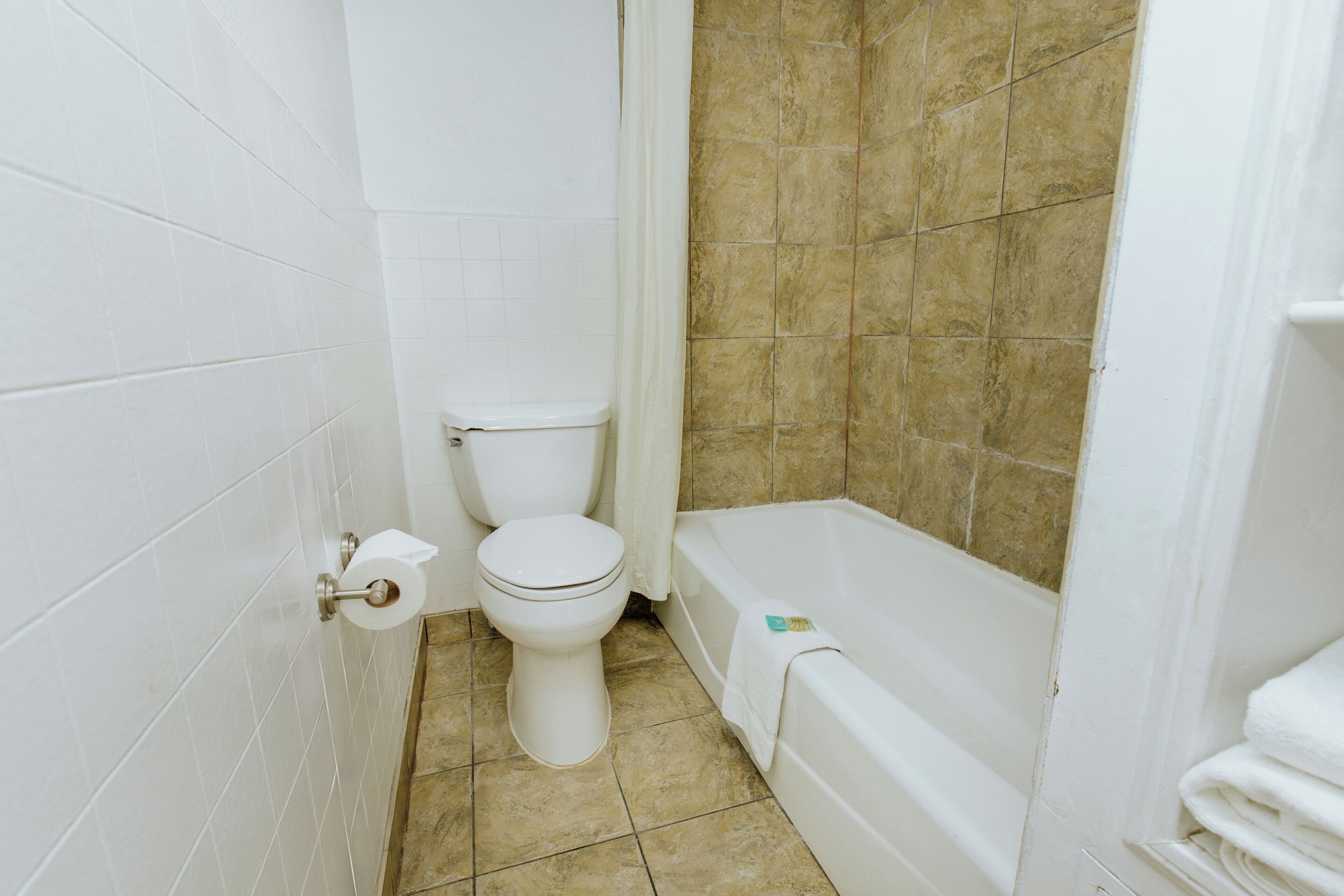 A bathroom with a toilet, bathtub, and tiled walls.
