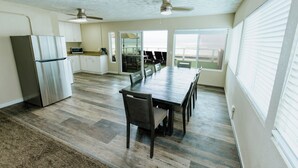 A spacious kitchen with a refrigerator, microwave, and dining area with chairs and a table. - Surfer Beach Hotel (San Diego)