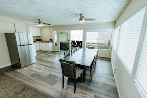 A spacious kitchen with a refrigerator, microwave, and dining area with chairs and a table. - Surfer Beach Hotel (San Diego)