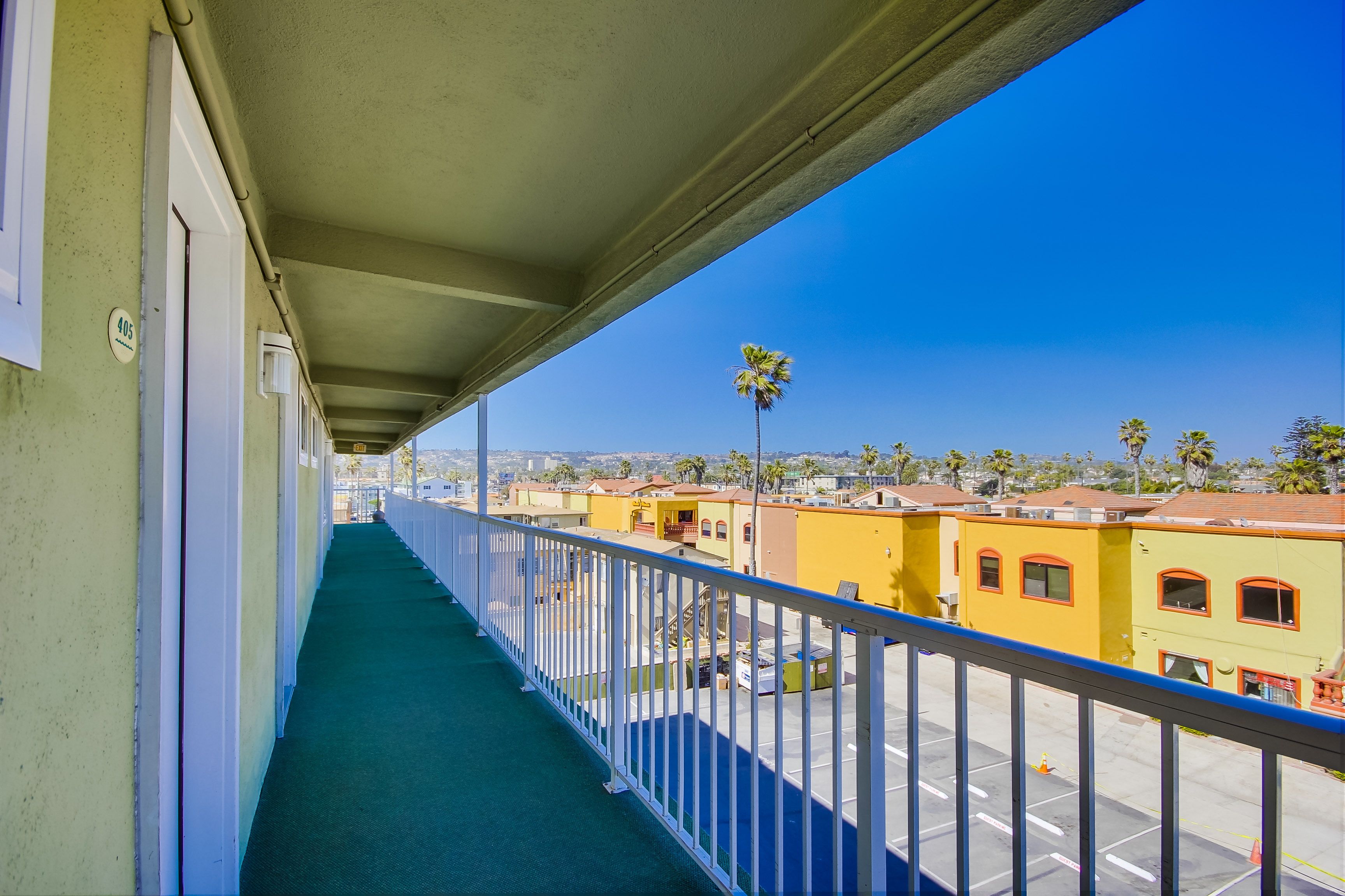 A balcony with a view of a parking lot and buildings.