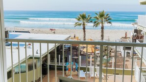 A balcony with a view of the beach, palm trees, and a pool area. - Surfer Beach Hotel (San Diego)