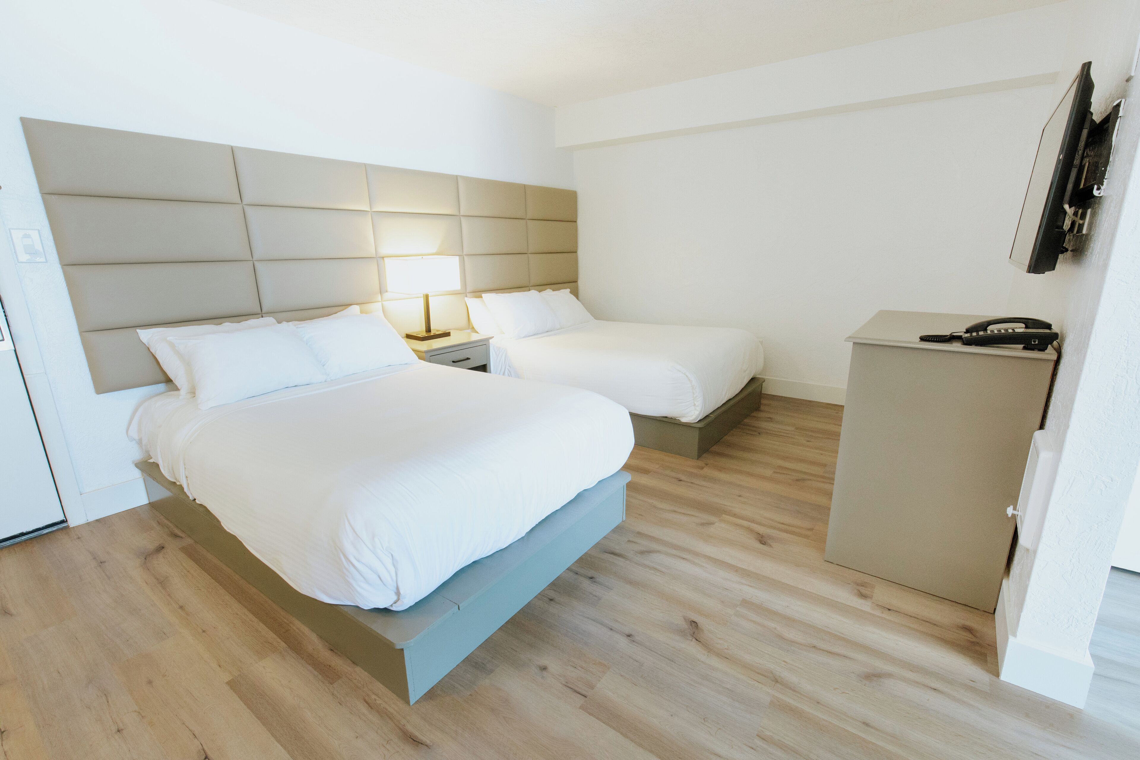 Une chambre d’hôtel avec un grand lit, deux tables de chevet, un bureau et un téléviseur à écran plat fixé au mur.
