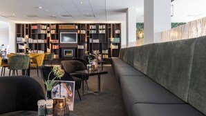 Un espace de détente moderne comprenant un canapé, des fauteuils, une cheminée et une bibliothèque.