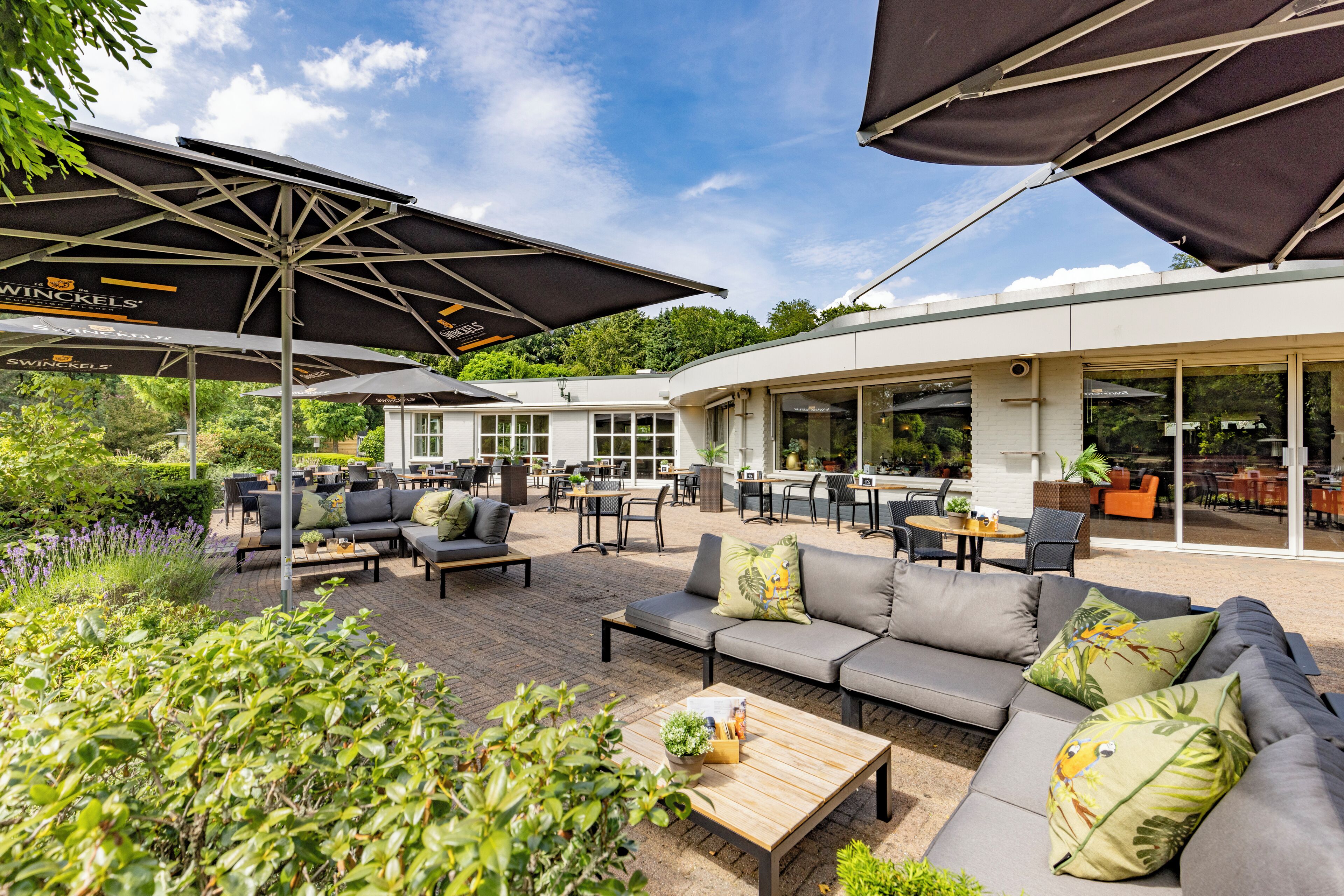 An outdoor seating area with sofas, tables, and umbrellas.