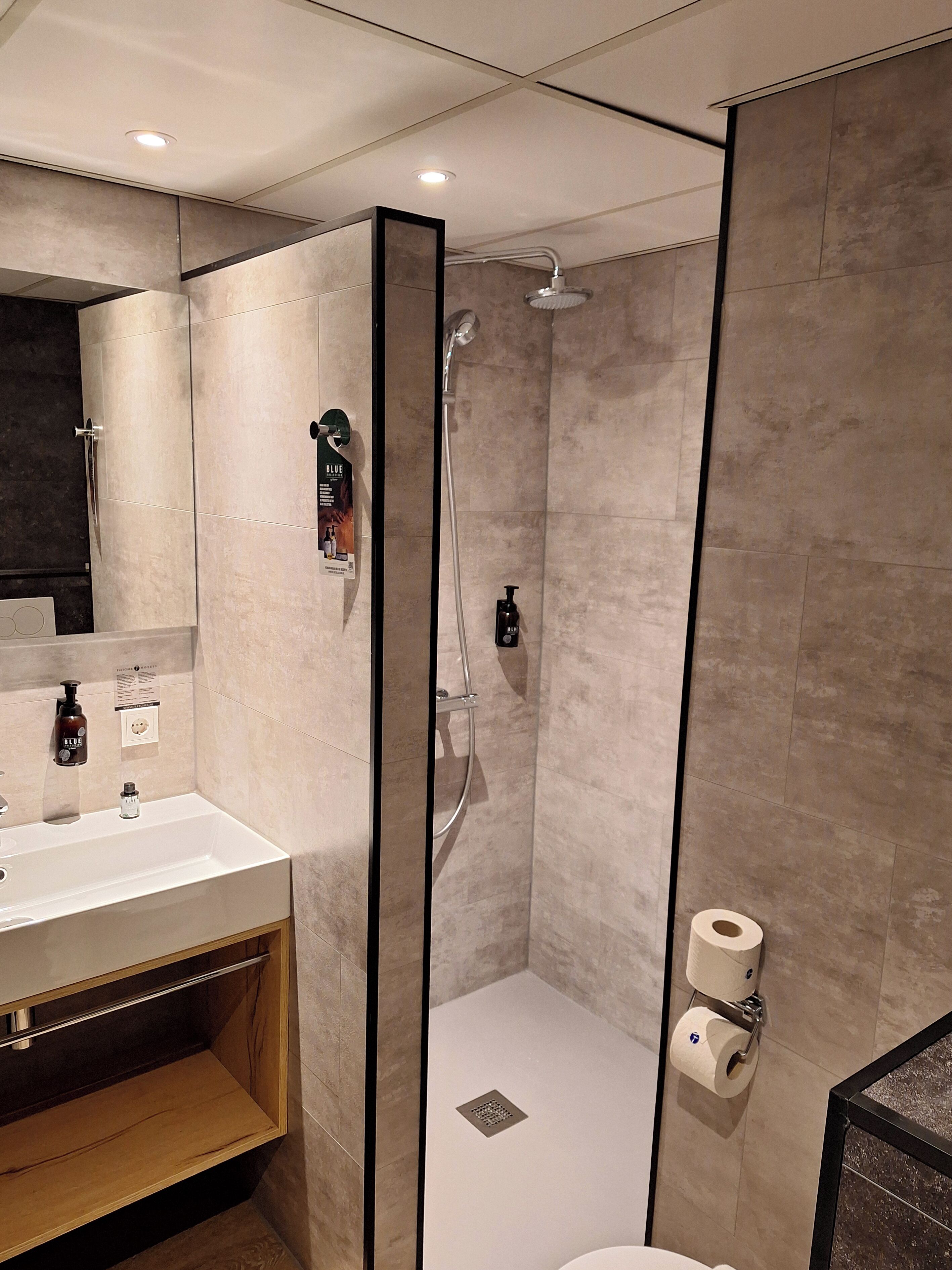 Ein modernes Badezimmer mit einer Duschkabine, einem Waschbecken mit Spiegel und einer Toilette.