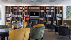 Une bibliothèque dotée d’étagères, d’une cheminée et d’espaces aménagés pour s’asseoir.