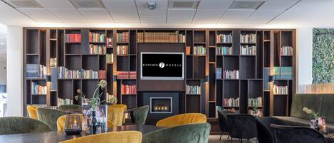 A library with bookshelves, a fireplace, and seating areas.