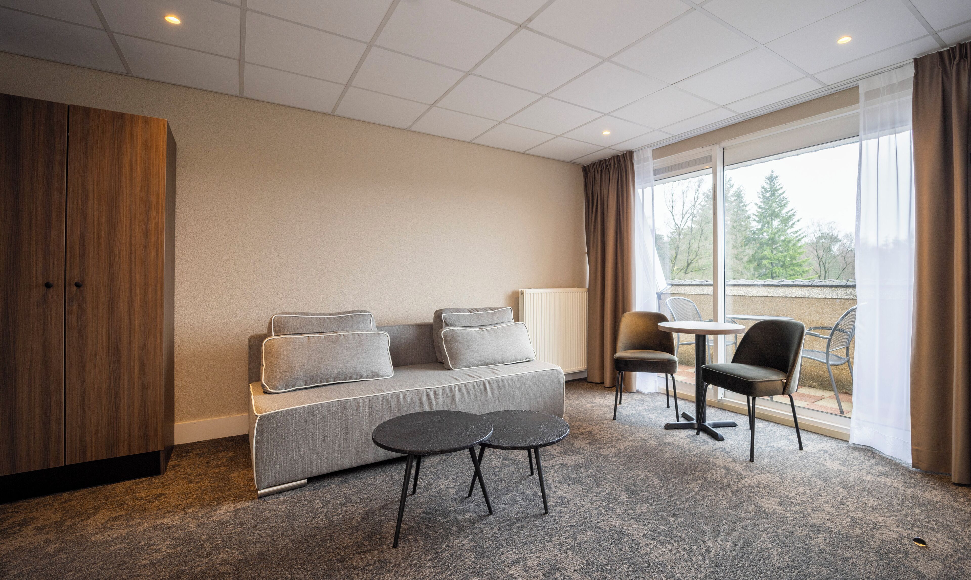 A modern room with a sofa, two small tables, and a view of the outdoors.