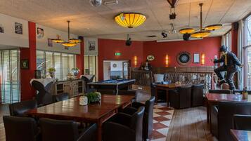 A billiards room with a pool table, seating area, and a dartboard.