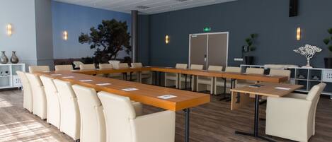 A conference room with a long table, several chairs, and a whiteboard.