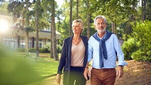 Two people walking on a path in a park-like setting with trees and a building in the background. - Hotel De Werelt Garderen (Garderen)