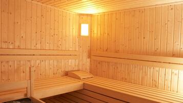 Una sala de sauna con bancos de madera y un banco con una bandeja de piedras.