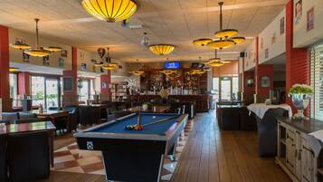 Un espace bar équipé de tables de billard, de sièges et d’un comptoir.
