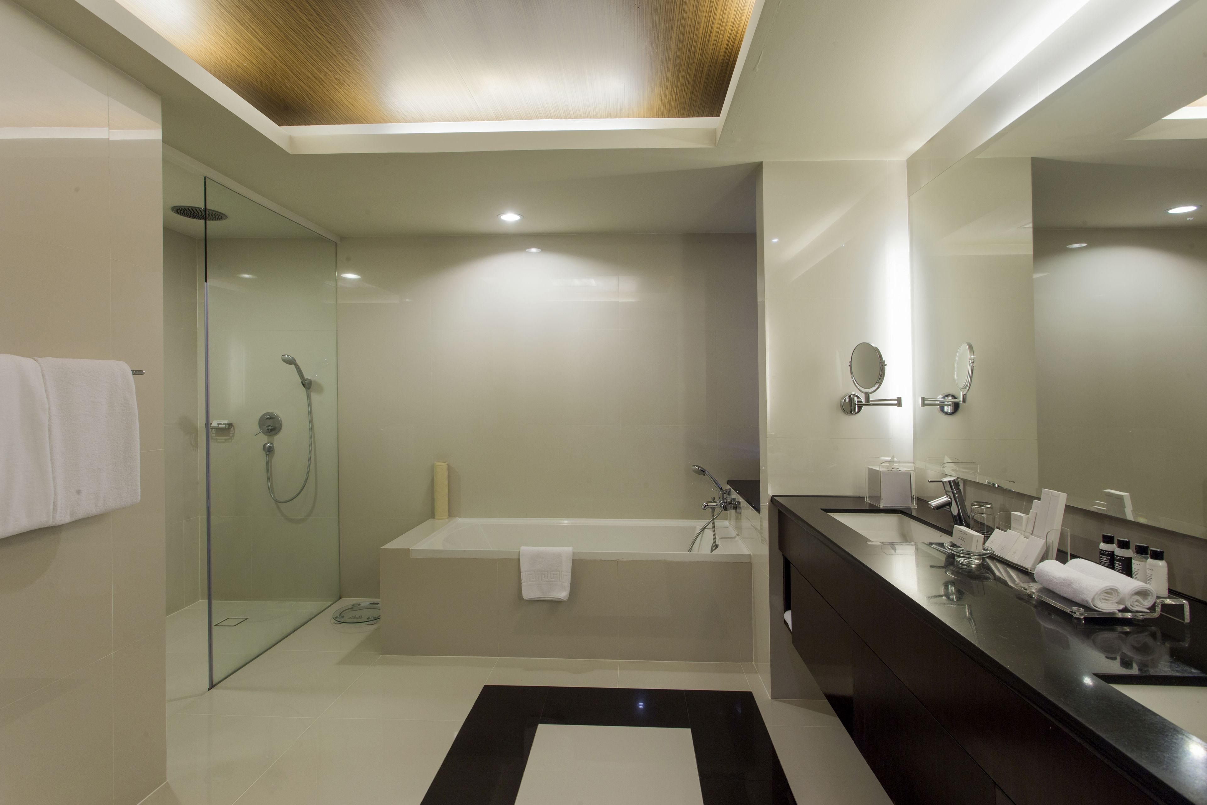 A modern bathroom with a glass-enclosed shower, a freestanding bathtub, and a dark vanity with a large mirror.
