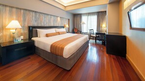 A hotel room with a large bed, bedside tables, a desk, and a chair. - The Bellevue Manila  (Muntinlupa)