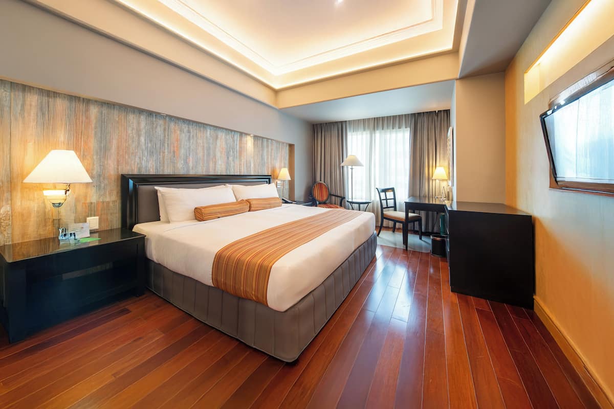 A hotel room with a large bed, bedside tables, a desk, and a chair.