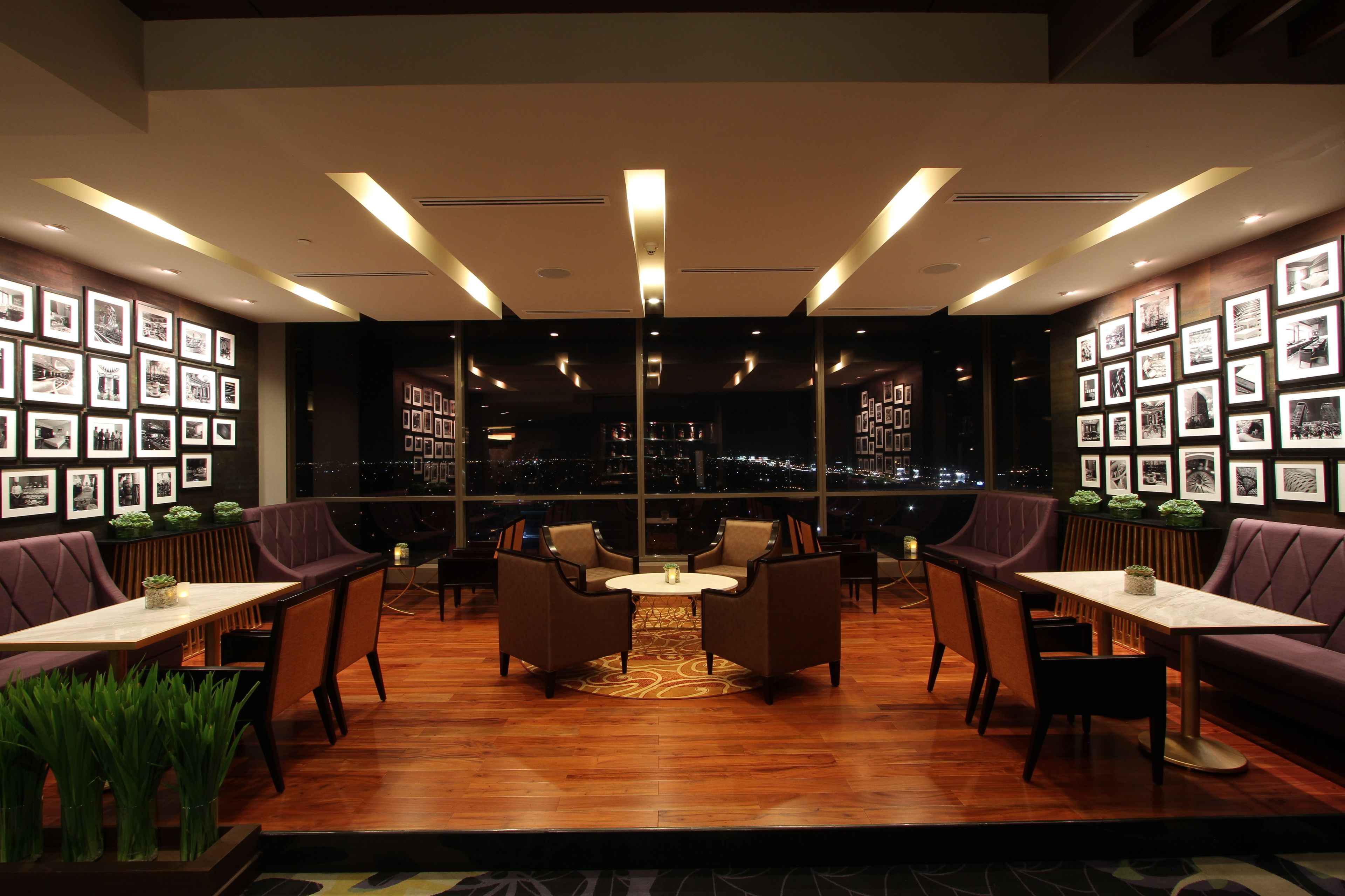 Un salón moderno con suelo de madera, asientos acolchados y cuadros enmarcados en las paredes.