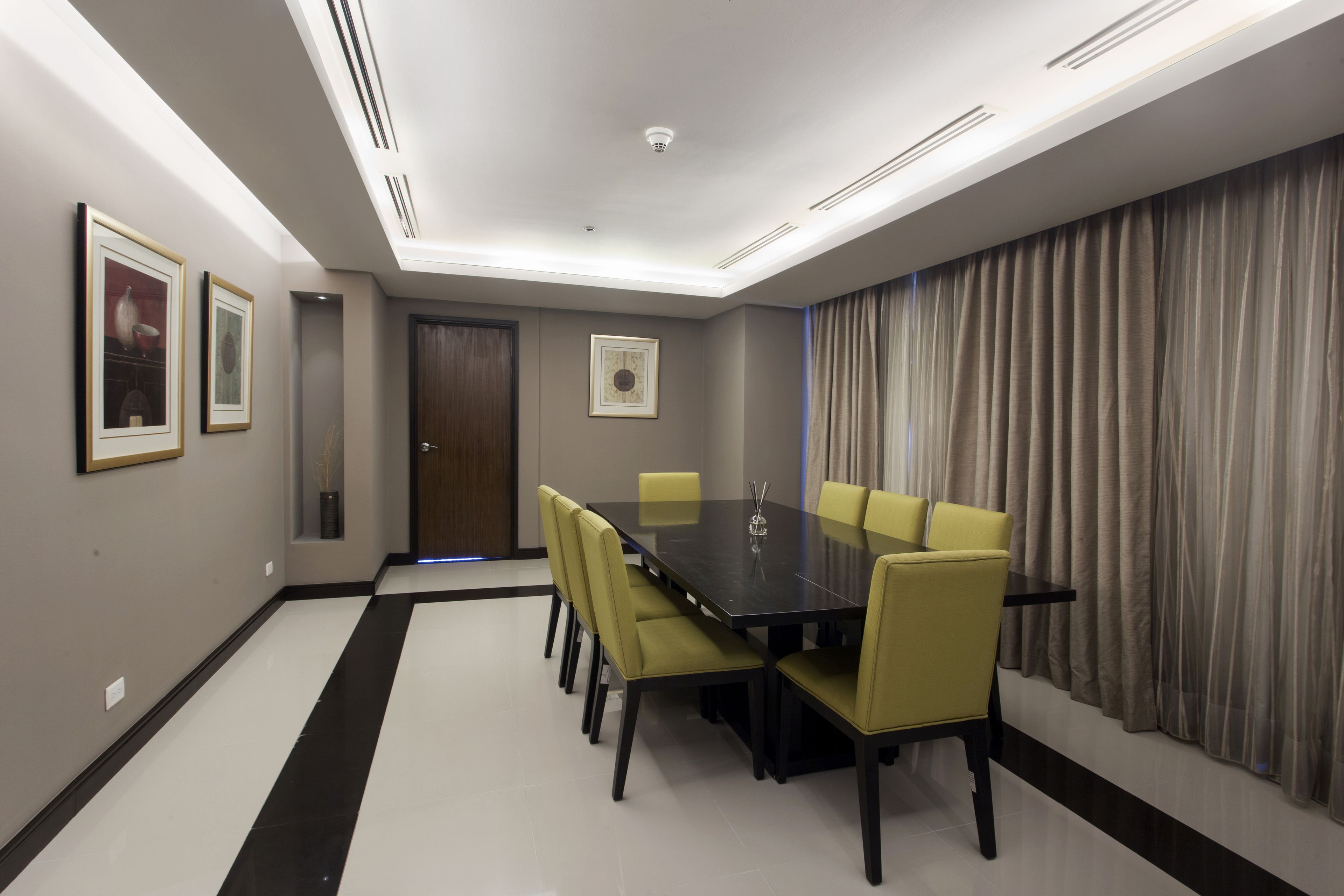 A conference room with a dark table, yellow chairs, a door, and a curtain.