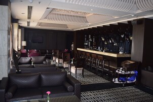 A modern bar area with leather seating, a bar counter, and a patterned floor.