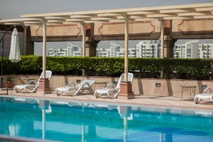 Ein Poolbereich mit Liegestühlen und einer Pergola.