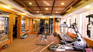 Academia com equipamentos de ginástica, bancos de madeira e um espelho grande.