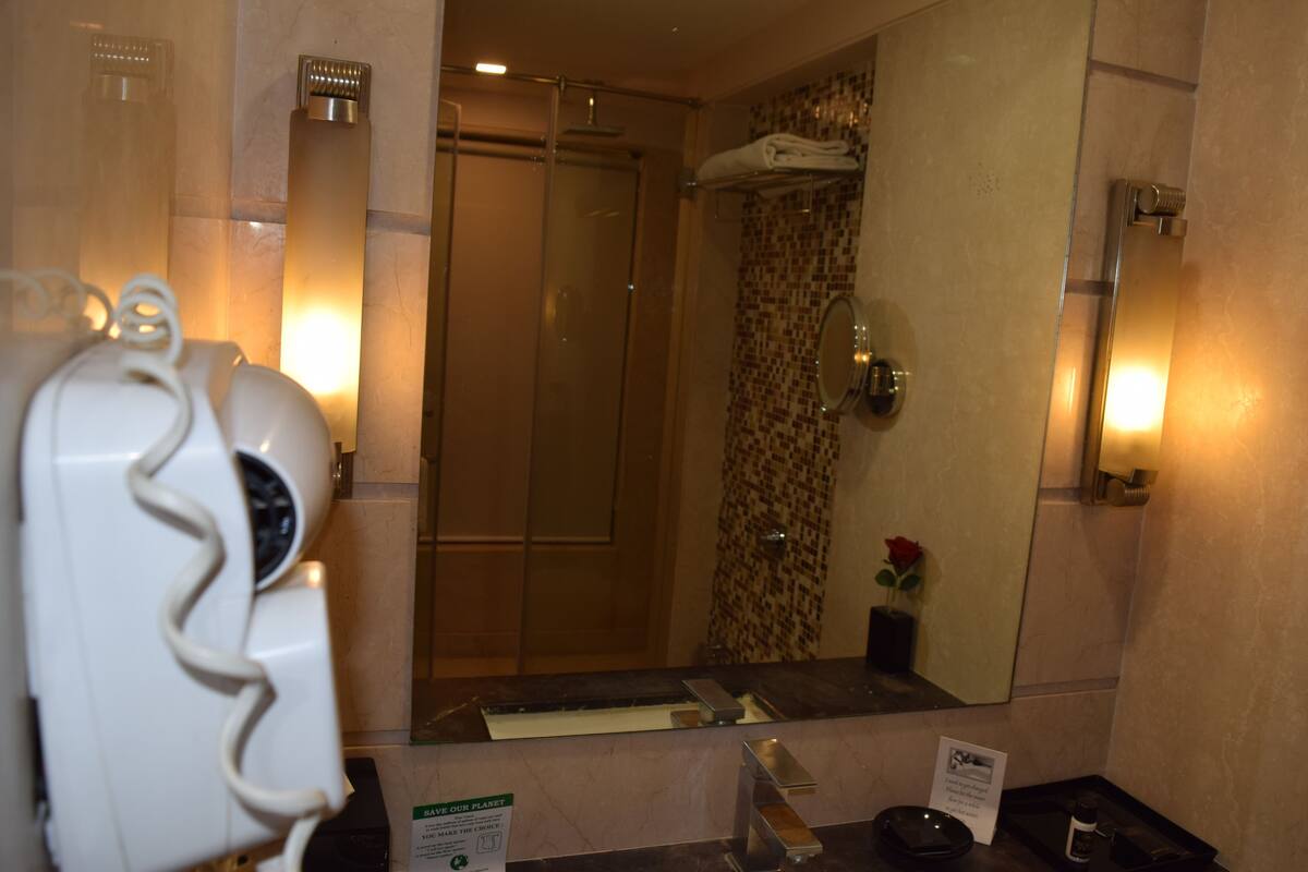 A bathroom with a shower, a towel rack, a sink, and a mirror.