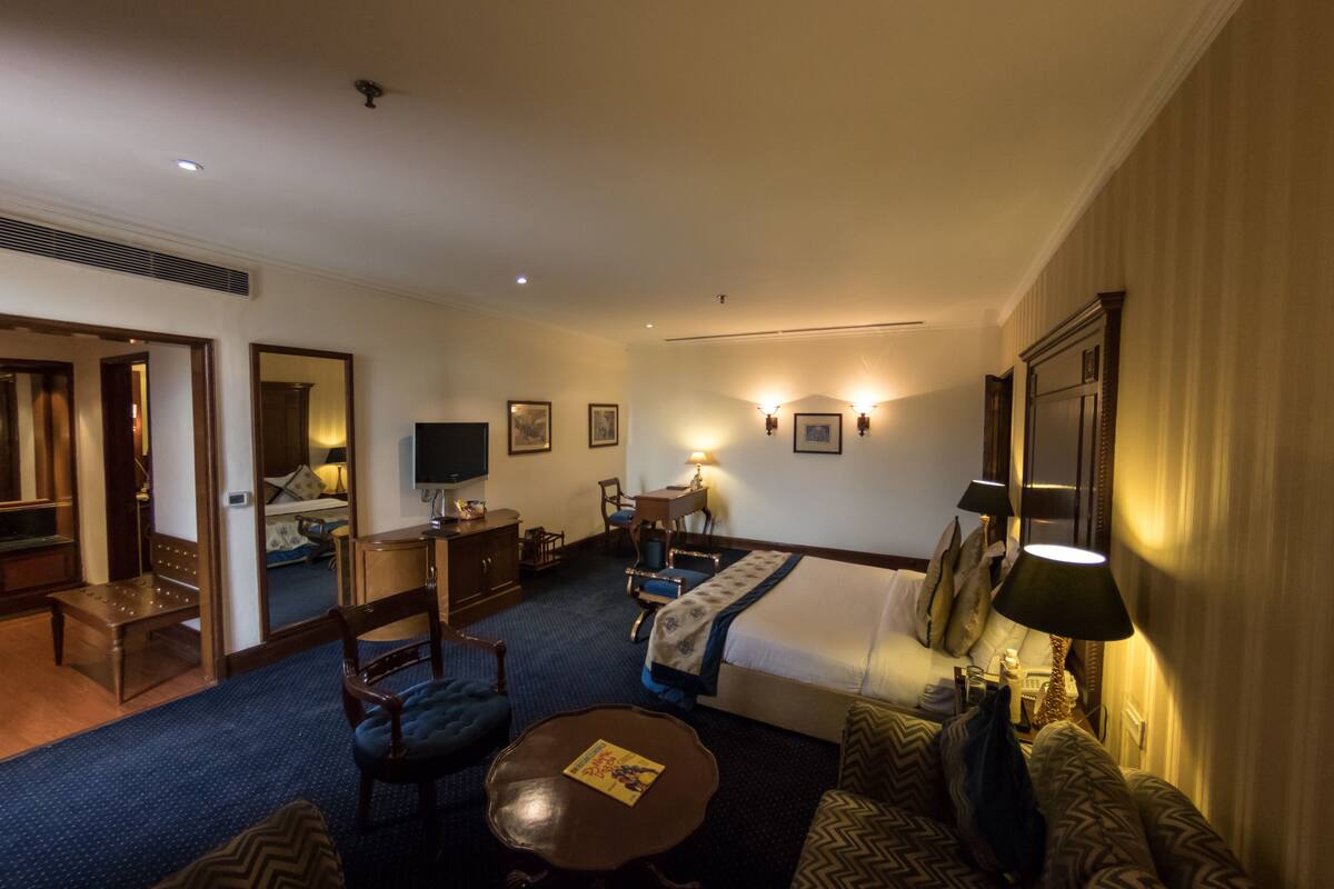 A hotel room with a bed, a desk, a television, a chair, and a sofa.