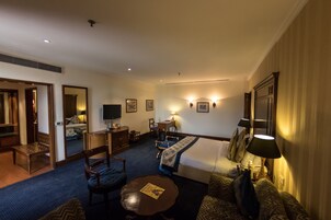 A hotel room with a bed, a desk, a television, a chair, and a sofa.